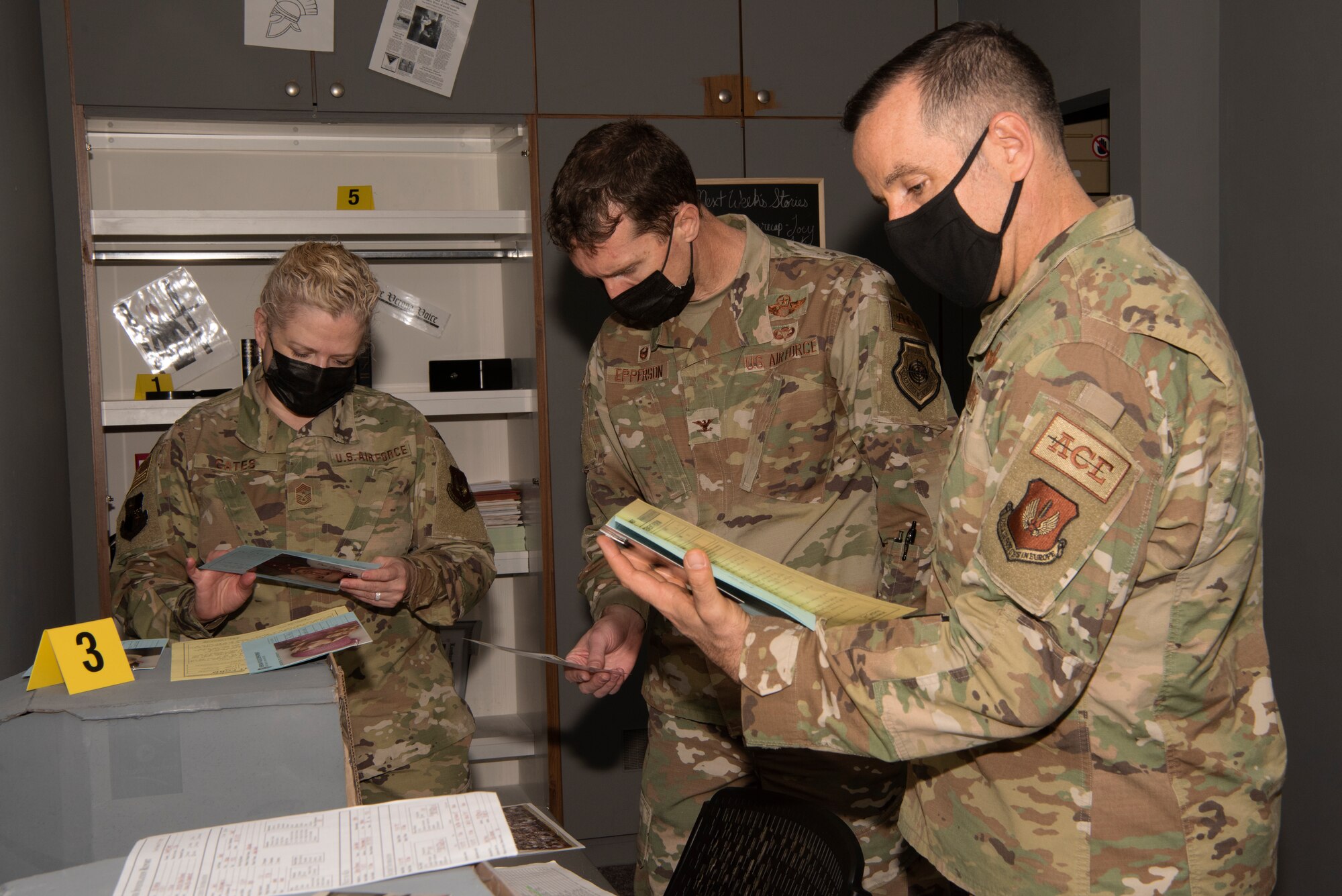 U.S. Air Force Col. David Epperson, 52nd Fighter Wing commander (center), U.S. Air Force Col. Jason Hokaj, 52nd FW vice commander (right), and U.S. Air Force Chief Master Sgt. Stephanie Cates, 52nd FW command chief (left), review clues placed in one of the two new escape rooms at Spangdahlem Air Base, Germany, May 14, 2021. The escape rooms were designed to boost morale and resiliency for units and families on Spangdahlem AB. (U.S. Air Force photo by Tech. Sgt. Tony Plyler)