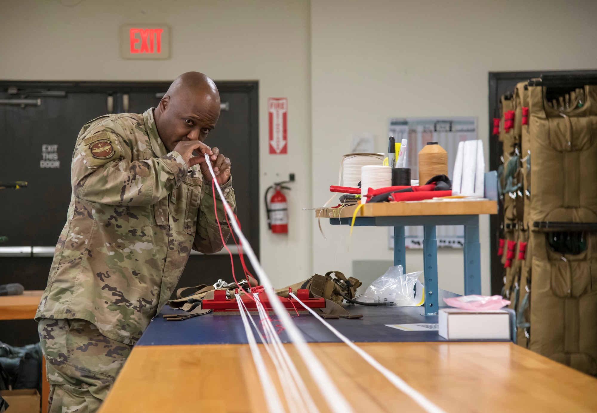 Tech. Sgt. Tyree Leverette, an aircrew flight equipment technician for the 403rd Operational Support Squadron at Keesler Air Force Base, Miss., unwinds the cords of a BA-30 Low Profile Parachute system before packing it May 2, 2021. The new parachute systems, in addition to being 25% lighter than the outgoing BA-22s, are designed to be less susceptible to accidental deployment.  (U.S. Air Force photo by Staff Sgt. Kristen Pittman)