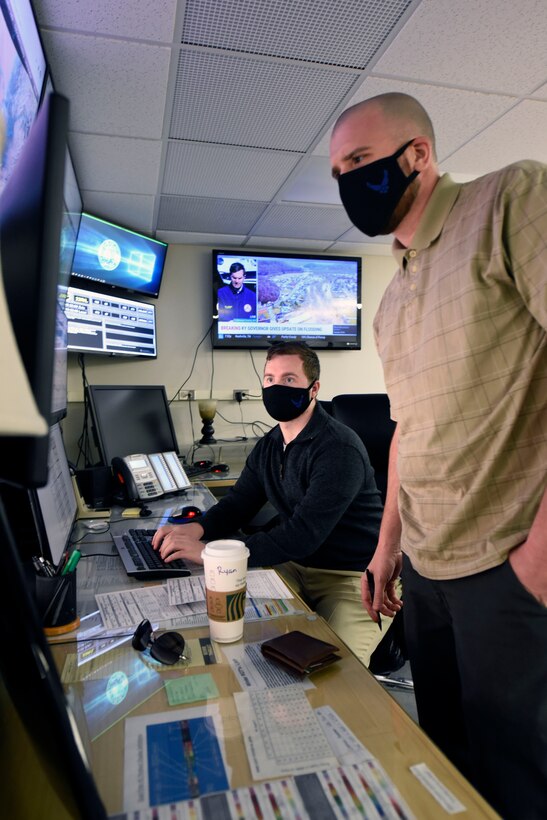Air Force contractors Ryan Balding, left, and Zach Grandin, 88th Operations Support Squadron weather technicians, discuss past weather systems in the Base Weather Station at Wright-Patterson Air Force Base, Ohio on March 2, 2021. The Base Weather Station operates with ten contactors, around the clock and supports the aviation mission through briefs, observations and forecasts, and the resource protection mission through watches, warnings and advisories. (U.S. Air Force photo by Ty Greenlees)