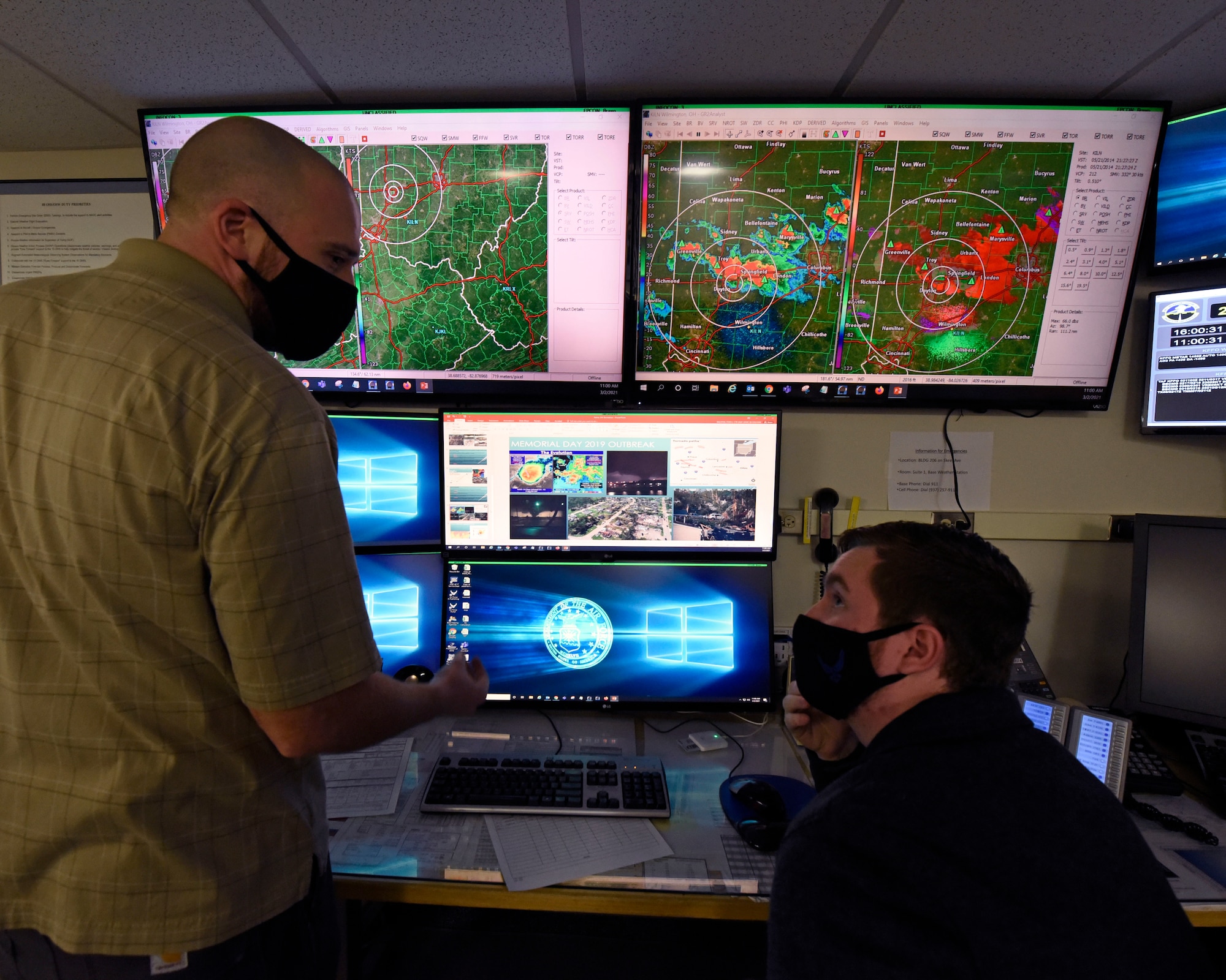 Air Force contractors Zach Grandin, left, and Ryan Balding, 88th Operations Support Squadron weather technicians, discuss past weather systems in the Base Weather Station at Wright-Patterson Air Force Base, Ohio on March 2, 2021. The Base Weather Station operates with ten contactors, around the clock and supports the aviation mission through briefs, observations and forecasts, and the resource protection mission through watches, warnings and advisories. (U.S. Air Force photo by Ty Greenlees)