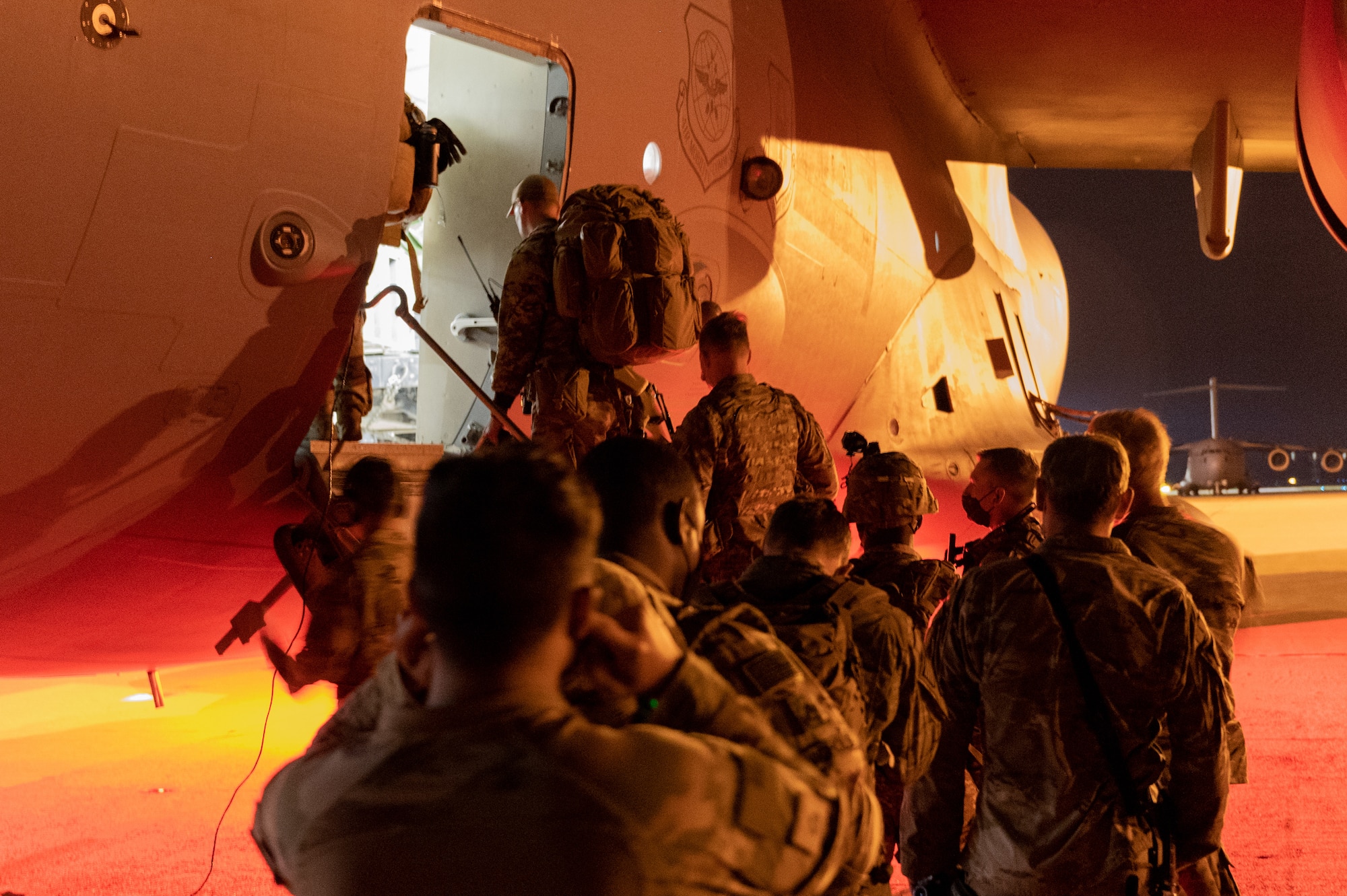 A line of Airmen and Soldiers boarding a cargo aircraft.