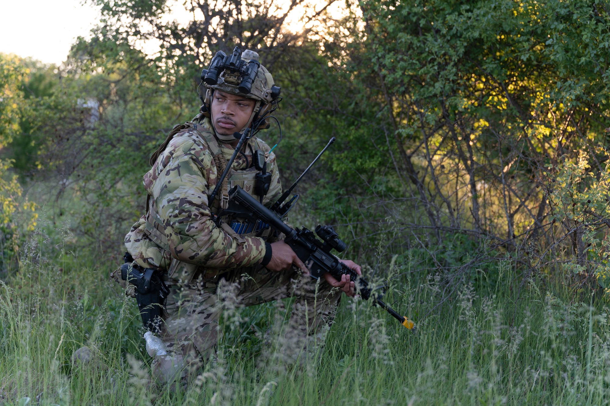 An airman standing in a field with combat gear.