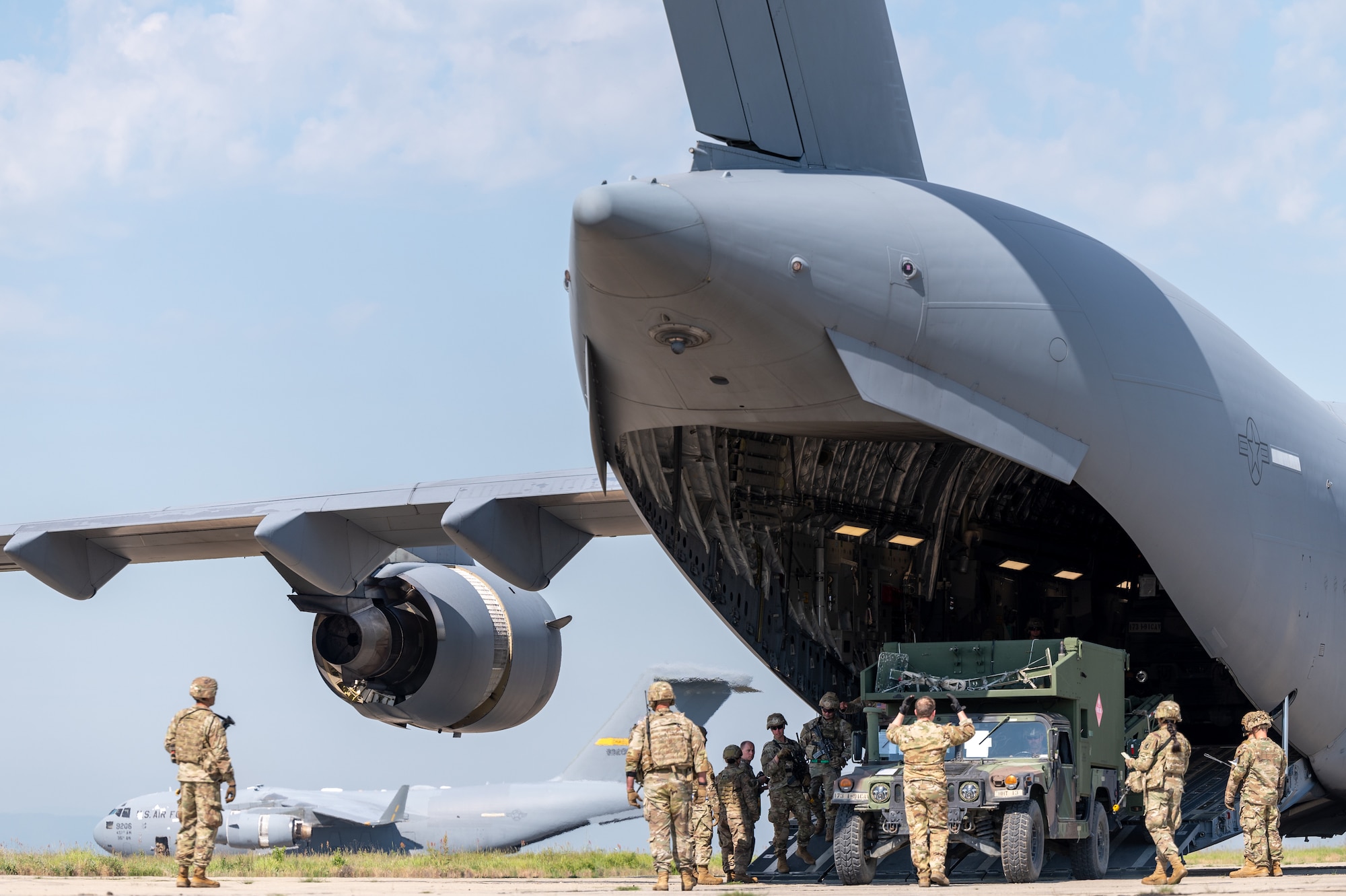Airmen and Soldiers standing next to an aircraft with its ramp down.