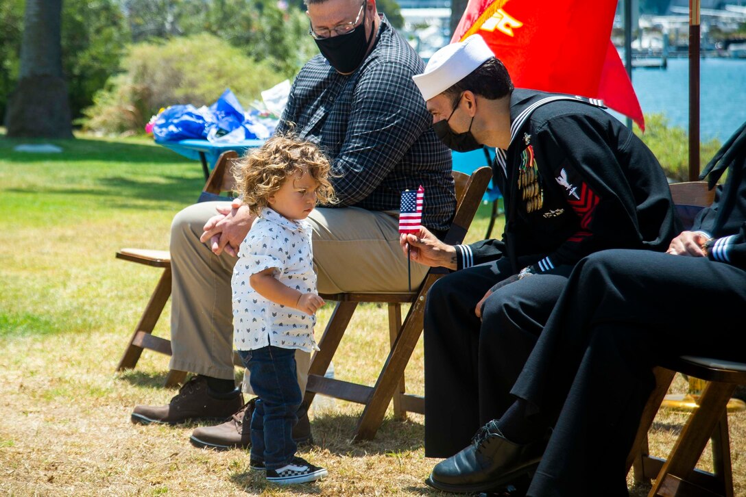 A sailor holds a flag given by a  child.