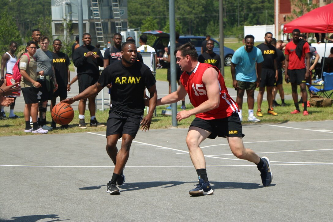 A soldier dribbles a ball while a fellow soldier plays defense.