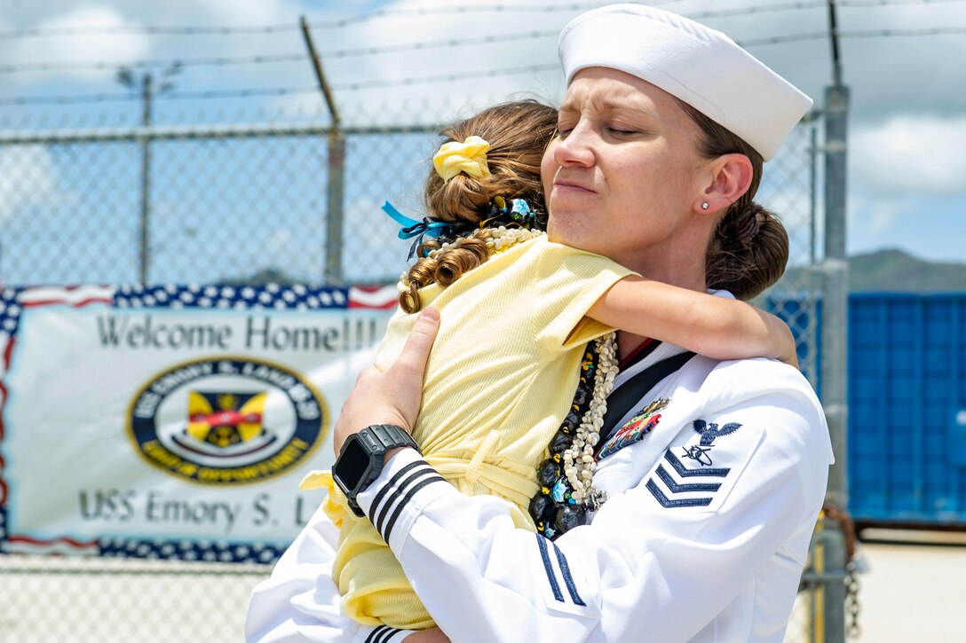 A sailor hugs her daughter.