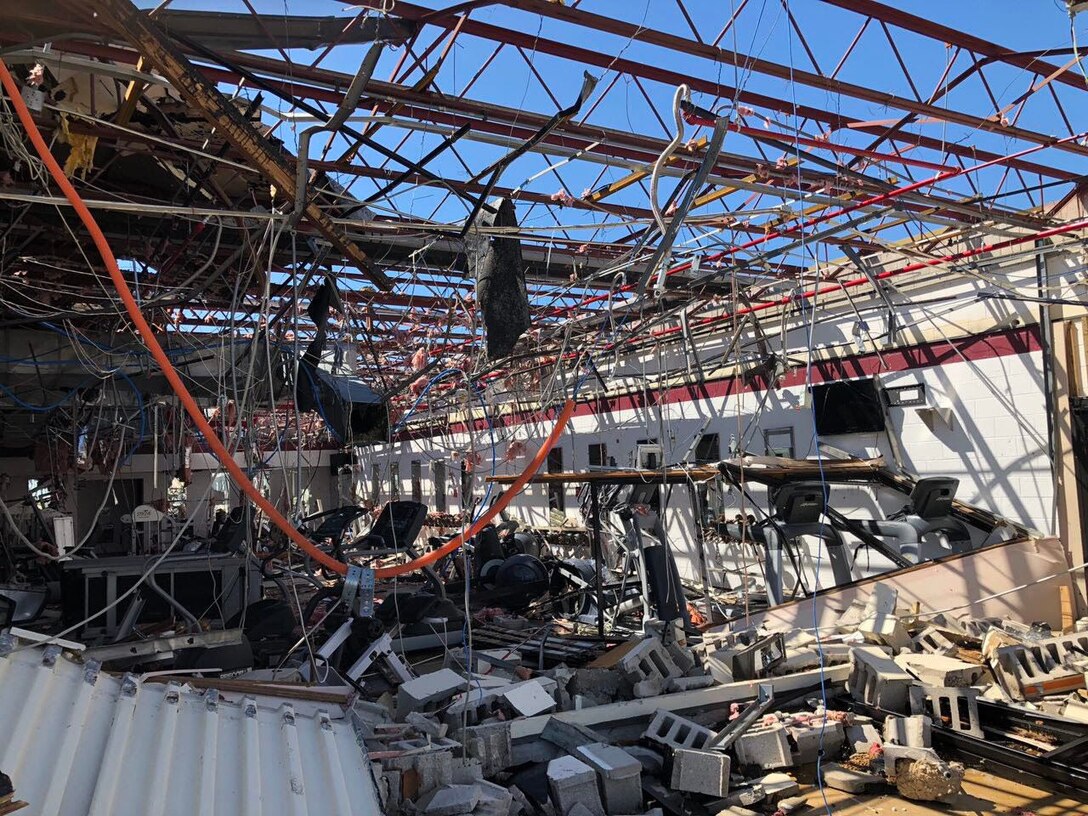 The sky is visible from inside a building where the roof has been ripped away. Rubble is strewn about.