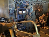 Airman in mask points while operating screen.