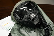 A gas mask on a table next to a piece of paper displaying a graph.