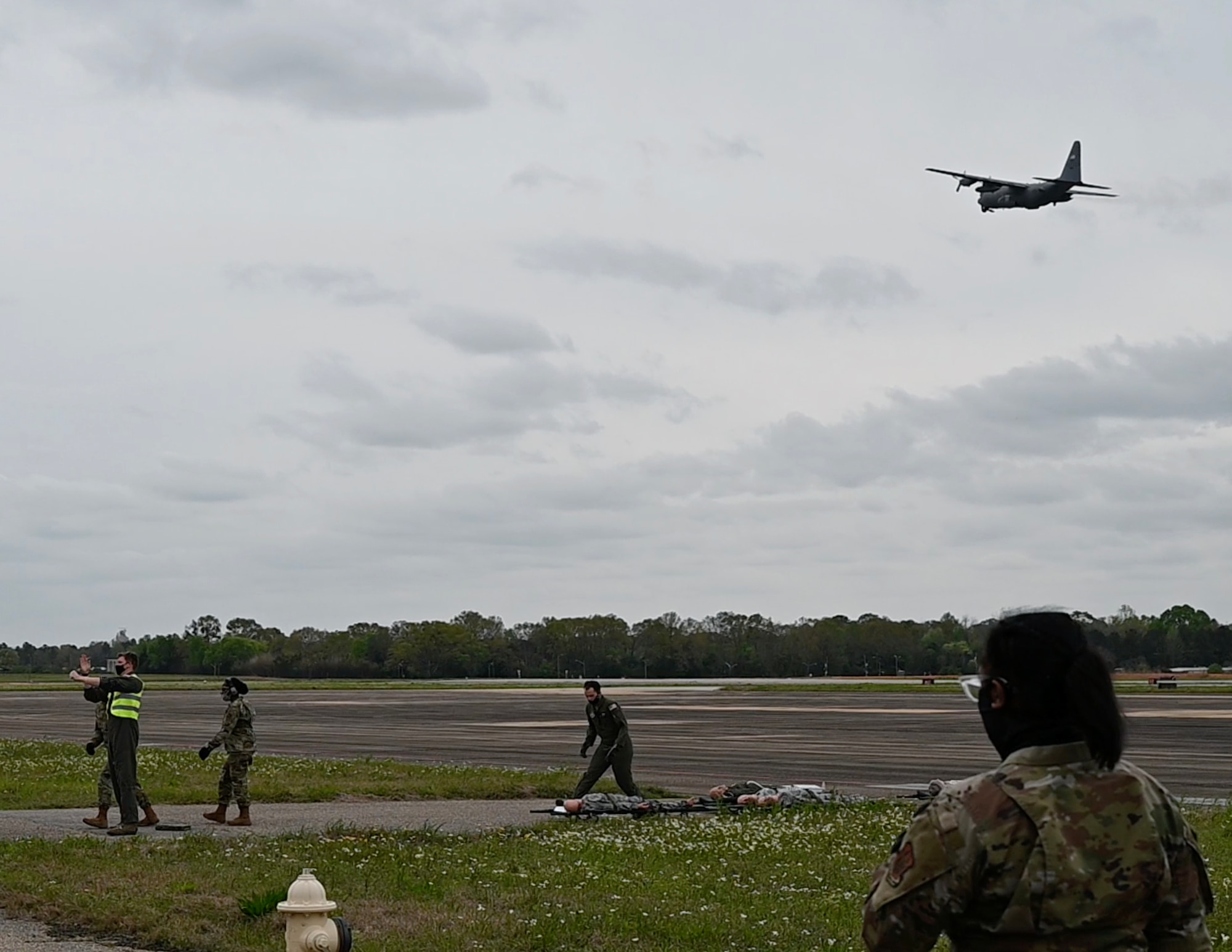 an aircraft flies overhead as people tend to patients.