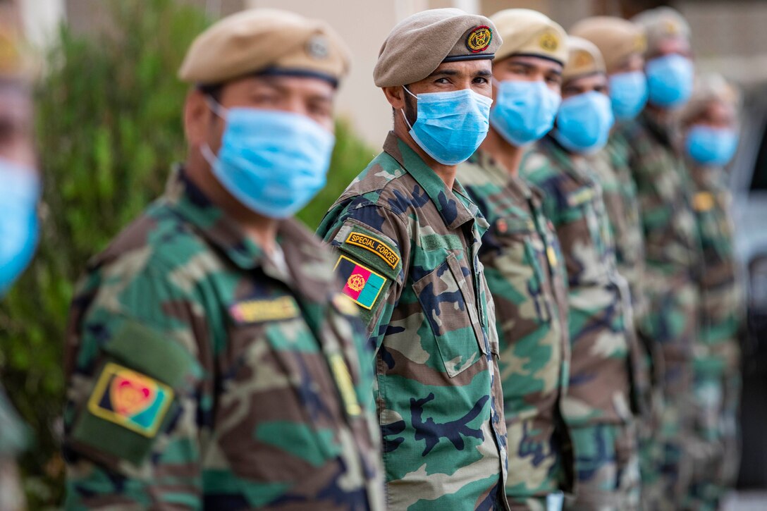 Multiple soldiers stand in a formation. Each wears a blue mask.