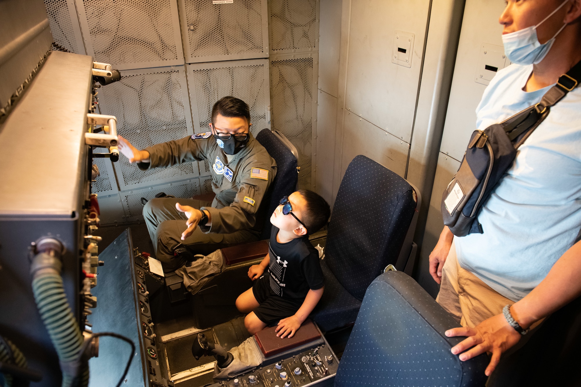 An Airmen in the boom operator compartment of a KC-10 Extender speaks to a child about being a boom operator for the Air Force.