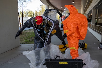 Tech Sgt. Eric McComb, 103rd Civil Support Team, and Sgt. Andrew Hunt, 103rd CST, assist each other with the decontamination process after responding to a simulated incident at a parking garage on the University of Alaska Anchorage campus May 18 in support of Exercise ORCA 2021. ORCA is a chemical, biological, radioactive, nuclear threats response exercise designed for participants to provide support in the aftermath of hazardous materials incidents. ORCA tests interoperability between agencies, increases opportunities for working relationships, and practices requests for assistance methods. Approximately 250 National Guardsmen from CST units in Alaska, California, Connecticut, Colorado, Idaho, Ohio, Oregon, Rhode Island, South Carolina, South Dakota, Washington, and Wisconsin are in Alaska to participate in Exercise ORCA 2021. Numerous support units and civilian agencies participated in the exercise as well. (U.S. Army National Guard photo by Spc. Grace Nechanicky)