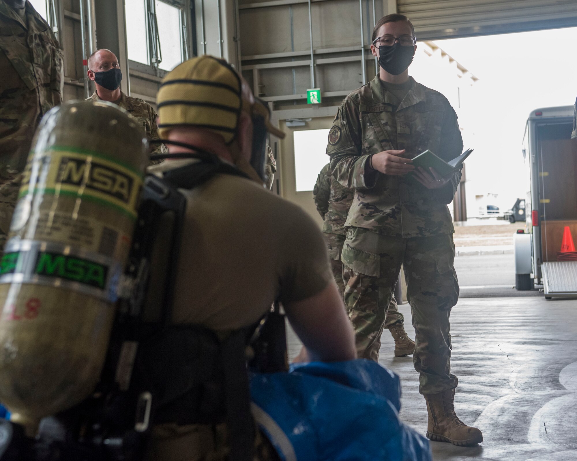 Man with an oxygen mask sits listening to a woman in uniform talking.