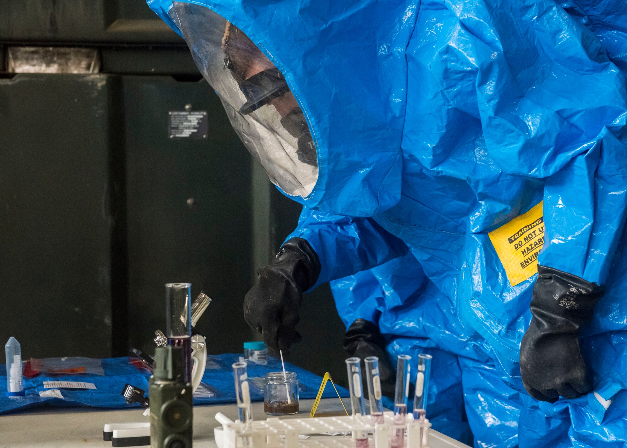 Man in hazmat suit collects and studies unknown samples on a table