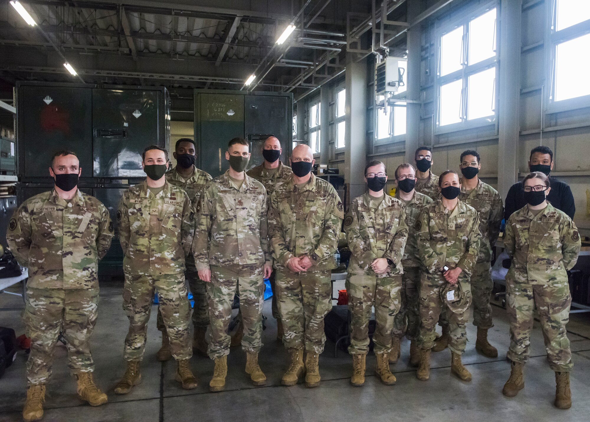 Group of Air Force members stand in a warehouse for a photo.