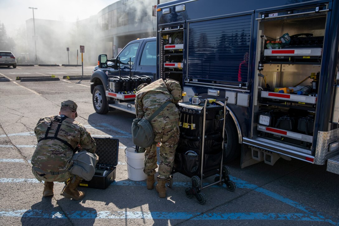 Sgt. Jason Williams, 103rd Civil Support Team, and Senior Airman Scottie Branson, 176th Civil Engineering Squadron, prepare gear to respond to a simulated incident at a parking garage on the University of Alaska Anchorage campus May 18, in support of Exercise ORCA 2021. ORCA is a chemical, biological, radioactive, nuclear threats response exercise designed for participants to provide support in the aftermath of hazardous materials incidents. ORCA tests interoperability between agencies, increases opportunities for working relationships, and practices requests for assistance methods. Approximately 250 National Guardsmen from CST units in Alaska, California, Connecticut, Colorado, Idaho, Ohio, Oregon, Rhode Island, South Carolina, South Dakota, Washington, and Wisconsin are in Alaska to participate in Exercise ORCA 2021. Numerous support units and civilian agencies participated in the exercise as well. (U.S. Army National Guard photo by Spc. Grace Nechanicky)