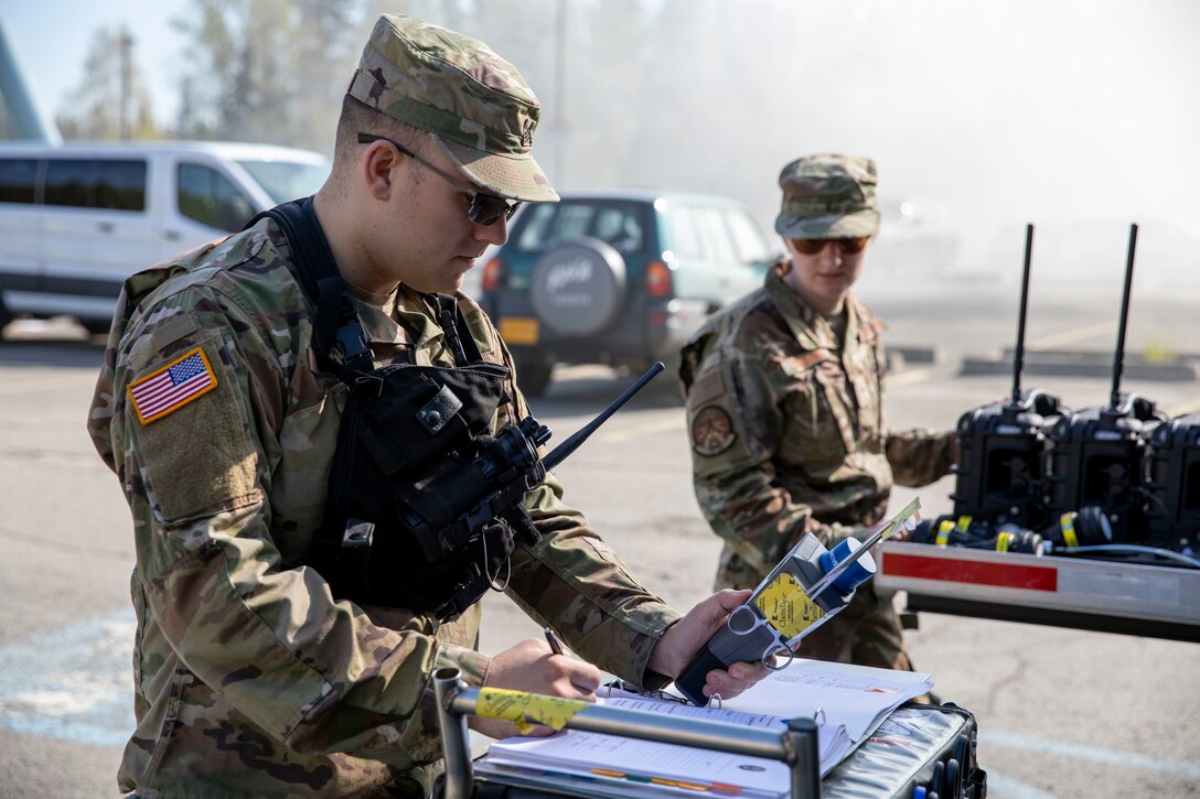 Sgt. Jason Williams, 103rd Civil Support Team, and Senior Airman Scottie Branson, 176th Civil Engineering Squadron, prepare gear to respond to a simulated incident at a parking garage on the University of Alaska Anchorage campus May 18, in support of Exercise ORCA 2021. ORCA is a chemical, biological, radioactive, nuclear threats response exercise designed for participants to provide support in the aftermath of hazardous materials incidents. ORCA tests interoperability between agencies, increases opportunities for working relationships, and practices requests for assistance methods. Approximately 250 National Guardsmen from CST units in Alaska, California, Connecticut, Colorado, Idaho, Ohio, Oregon, Rhode Island, South Carolina, South Dakota, Washington, and Wisconsin are in Alaska to participate in Exercise ORCA 2021. Numerous support units and civilian agencies participated in the exercise as well. (U.S. Army National Guard photo by Spc. Grace Nechanicky)