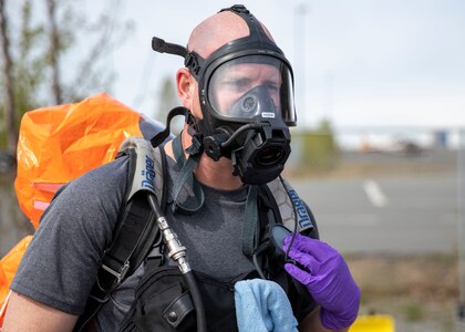 Sgt. Anthony Luiken, 103rd Civil Support Team, performs radio checks through his mask in preparation to respond to a simulated incident in a tower at the Anchorage Fire Training Center, May 19, in support of Exercise ORCA 2021. ORCA is a chemical, biological, radioactive, nuclear threats response exercise designed for participants to provide support in the aftermath of hazardous materials incidents. ORCA tests interoperability between agencies, increases opportunities for working relationships, and practices requests for assistance methods. Approximately 250 National Guardsmen from CST units in Alaska, California, Connecticut, Colorado, Idaho, Ohio, Oregon, Rhode Island, South Carolina, South Dakota, Washington, and Wisconsin are in Alaska to participate in Exercise ORCA 2021. Numerous support units and civilian agencies participated in the exercise as well. (U.S. Army National Guard photo by Spc. Grace Nechanicky)