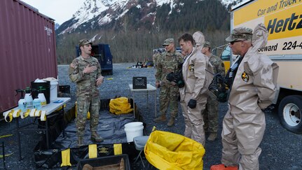 Staff Sgt. Taylor Dextradeur, training noncommissioned officer, 13th Civil Support Team, Rhode Island National Guard, briefs the decontamination process prior to the initial entry into the simulated incident site at the Port of Seward Drydocks in Seward, Alaska, May 18, in support of Exercise ORCA 21. ORCA is a chemical, biological, radioactive, nuclear threats response exercise designed for participants to provide support in the aftermath of hazardous materials incidents. ORCA tests interoperability between agencies, increases opportunities for working relationships, and practices requests for assistance methods. Approximately 250 National Guardsmen from CST units in Alaska, California, Connecticut, Colorado, Idaho, Ohio, Oregon, Rhode Island, South Carolina, South Dakota, Washington, and Wisconsin are in Alaska to participate in Exercise ORCA 2021. Numerous support units and civilian agencies participated in the exercise as well. (U.S. Army National Guard photo by Dana Rosso)