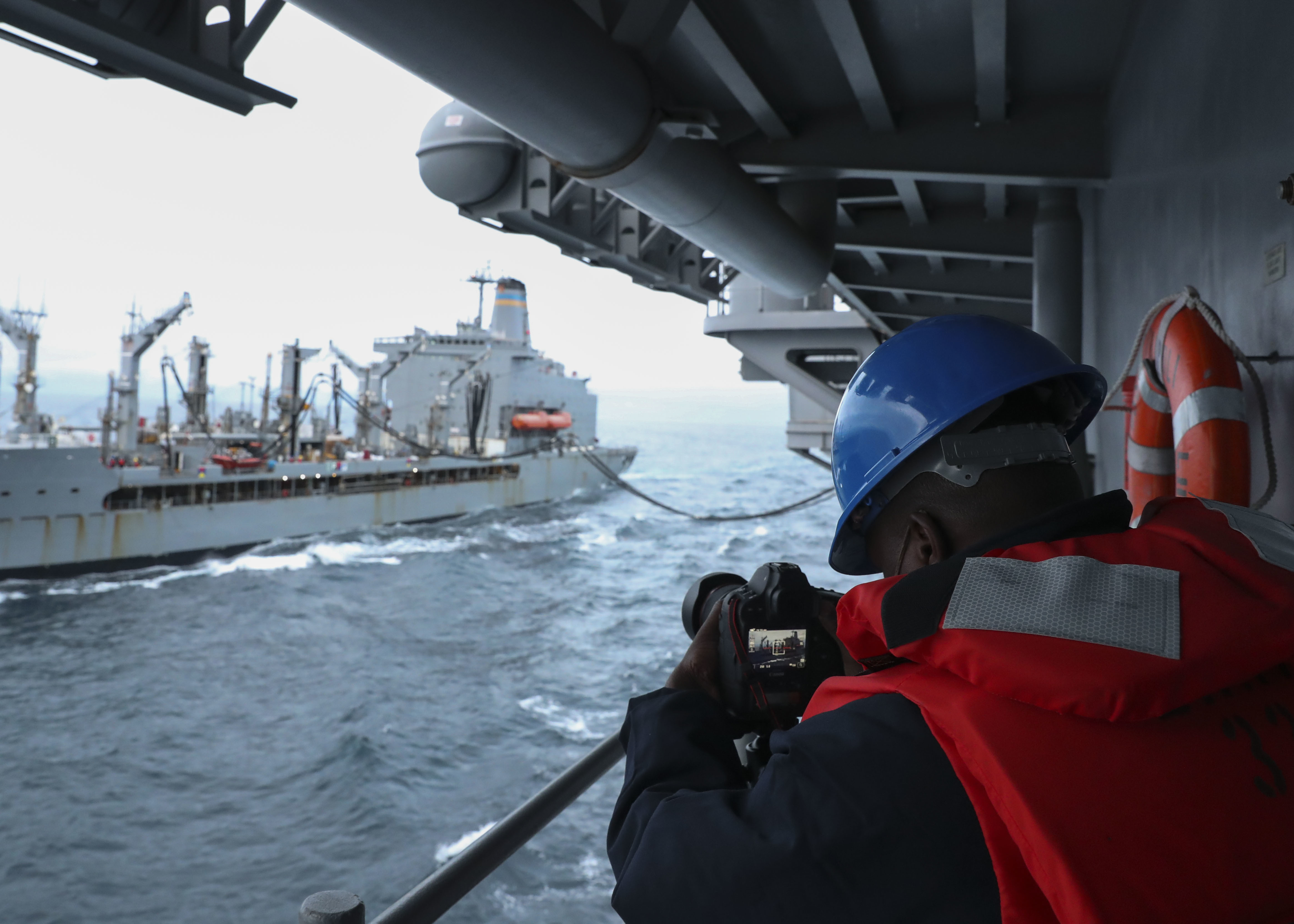 Mass Communication Specialist Seaman Melvin Fatimehin records video of USNS Henry J. Kaiser (T-AO 187) refueling USS Tripoli (LHA 7) during Tripoli�s first replenishment-at-sea (RAS), May 16.