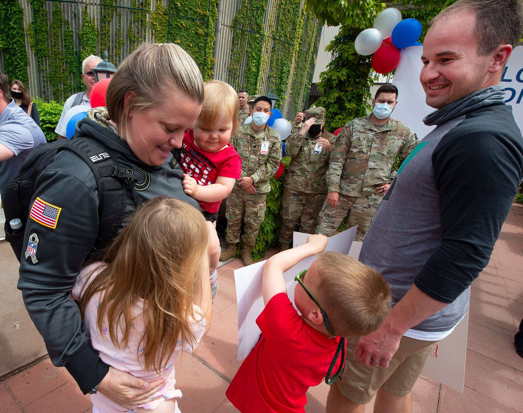 U.S. Air Force Maj. Evelyn Eyer hugs her children, Isla, Reagan and Brent shortly after she stepped off the bus May, 18, 2021, at the Wright-Patterson Air Force Base, Ohio, Medical Center returning from a two-month deployment to Detroit. Eyer, a nurse with the 88th Medicine Squadron, was one of more than a hundred Airmen who deployed from the base to Detroit to help at a mass vaccination site. (U.S. Air Force photo by R.J. Oriez)