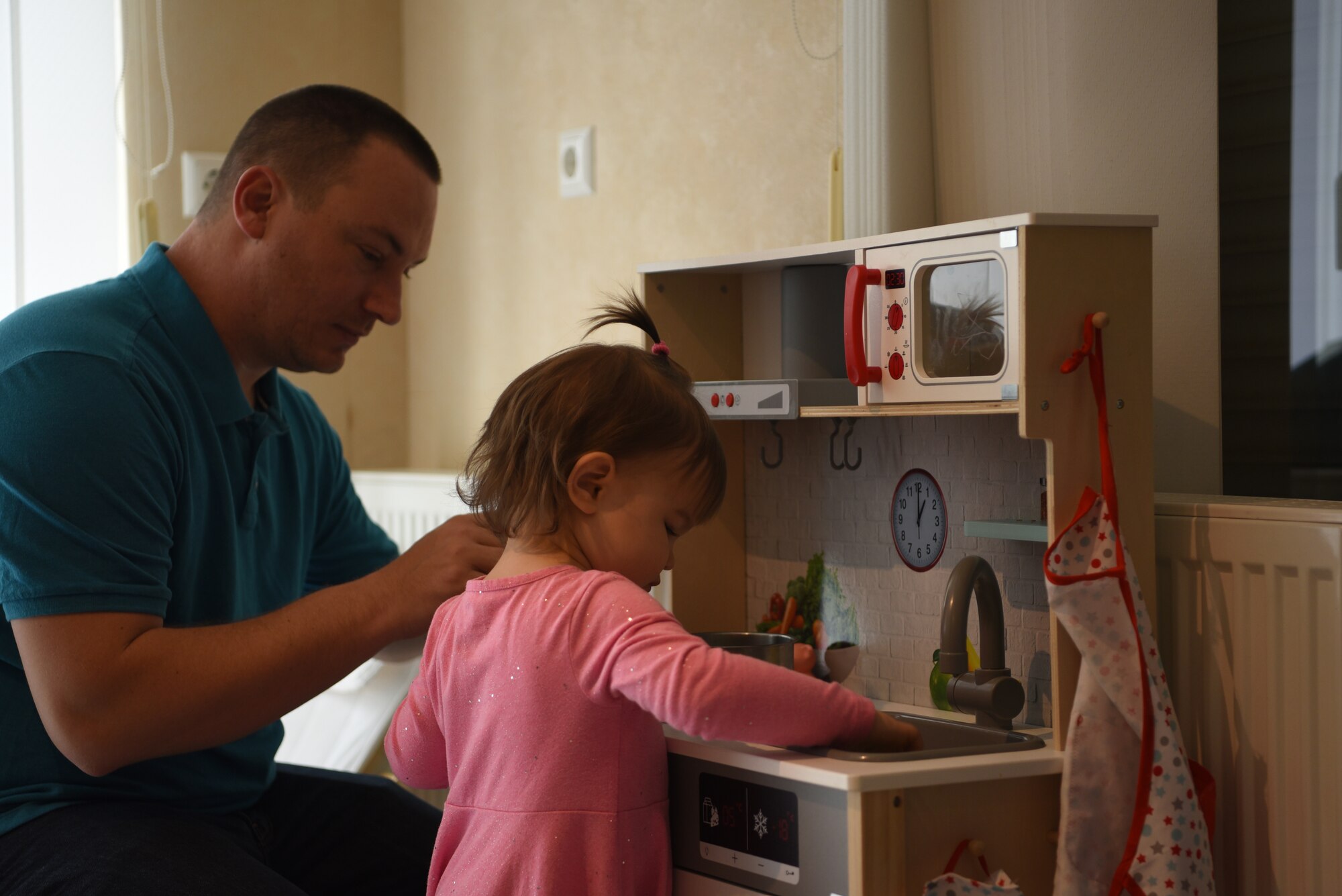 U.S. Air Force Tech. Sgt. Edwin Bowser, 569th U.S. Forces Police Squadron flight sergeant, plays alongside his daughter Elsie, in their home.