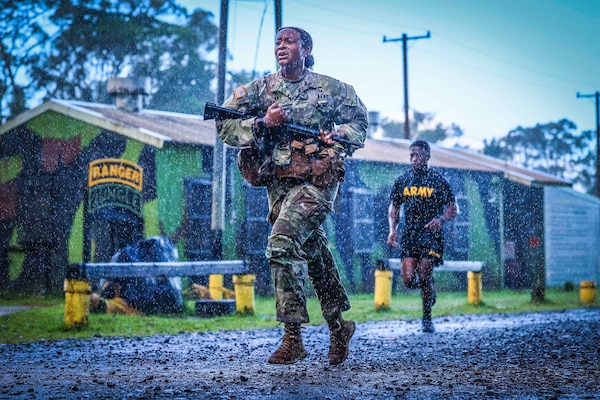 A soldier carries a weapon while running in the rain.