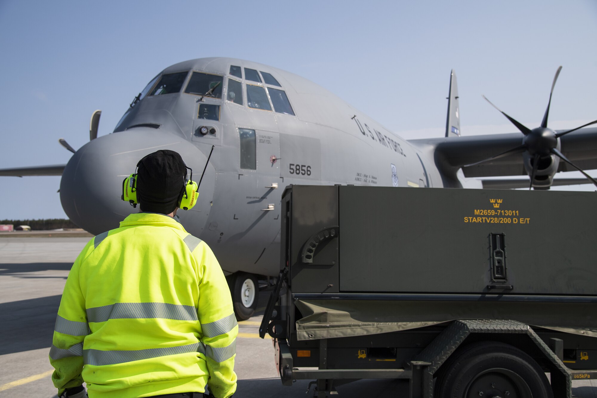 An employee at Kallax Air Base, Sweden, waits for a U.S. Air Force C-130 Hercules aircraft to unload cargo at Kallax AB, Sweden, May 14, 2021. The aircraft deployed from the 86th Airlift wing at Ramstein Air Base, Germany, in support of Arctic Challenge Exercise 2021. (U.S. Air Force photo by Senior Airman Ali Stewart)