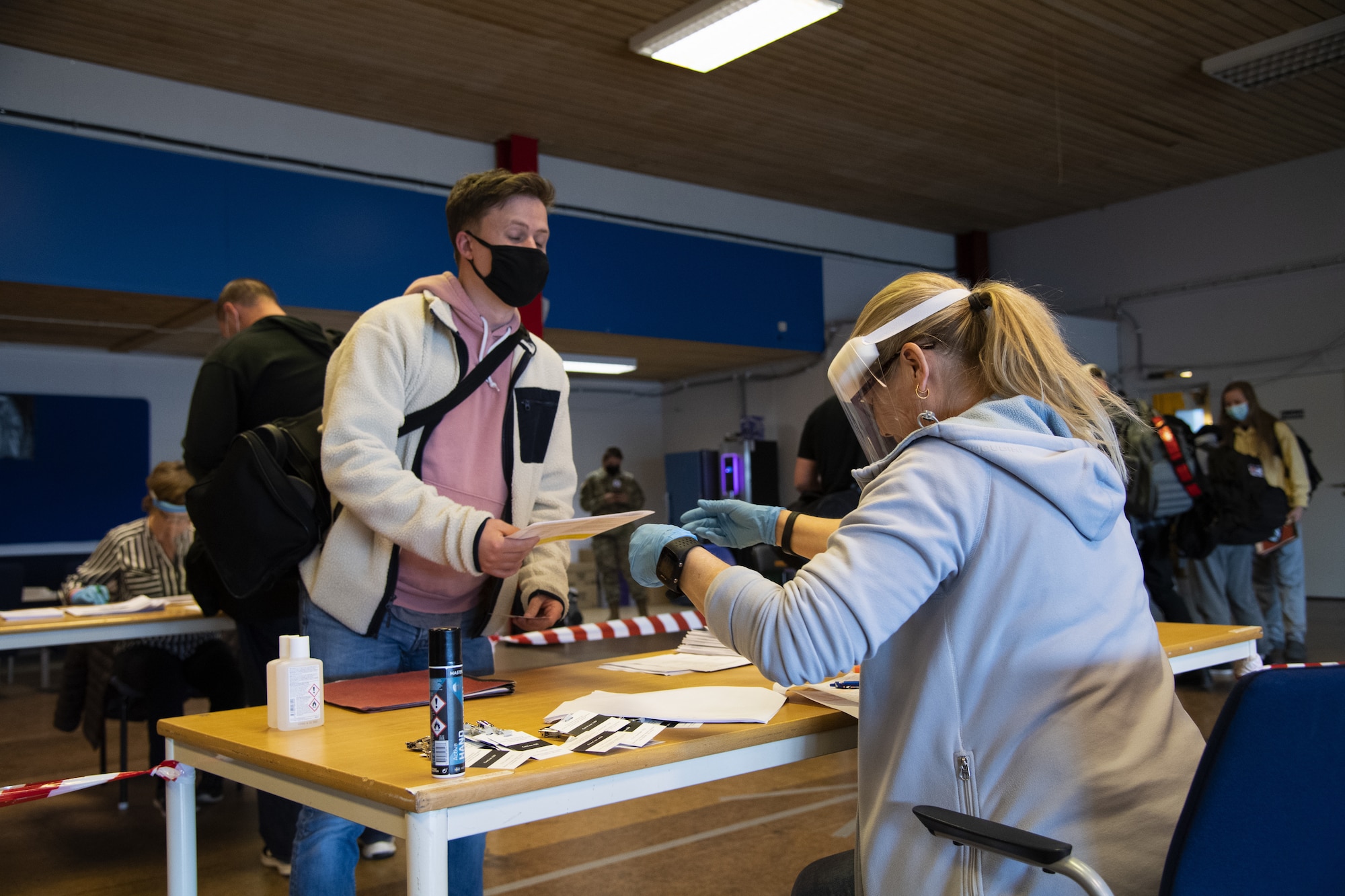 A U.S. Air Force Airman from Spangdahlem Air Base, Germany, left, presents paperwork to a Swedish border control employee at Kallax Air Base, Sweden, May 14, 2021. Airmen from the 52nd Fighter Wing at Spangdahlem Air Base took multiple precautions related to COVID-19 prior to entering Sweden to ensure a safe, healthy, and successful exercise for the entire duration of Arctic Challenge 2021. (U.S. Air Force photo by Senior Airman Ali Stewart)