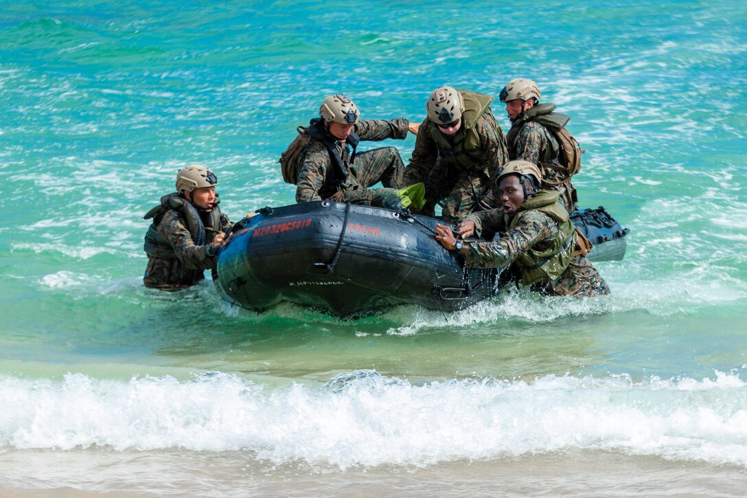 Marines in a combat rubber raiding craft move toward a shore.