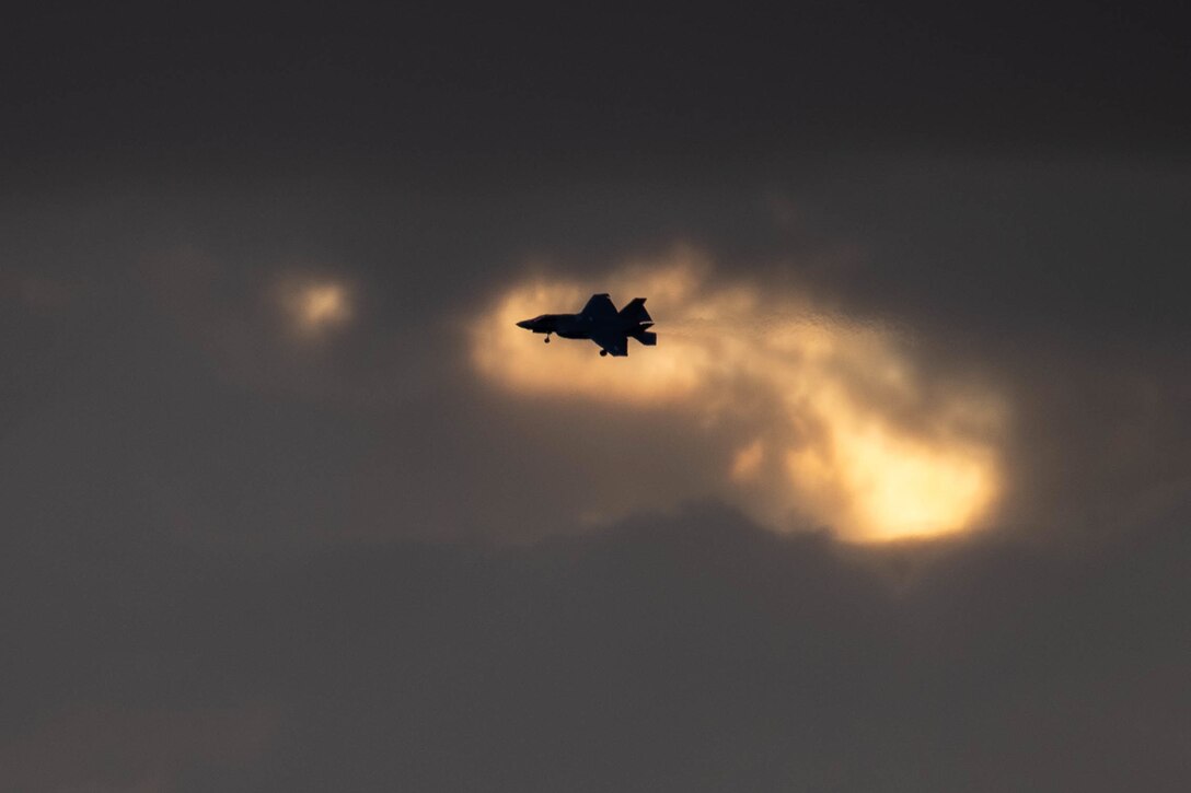 An aircraft in silhouette prepares to land.