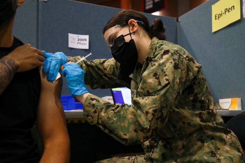 A sailor gives a person a shot in the arm.