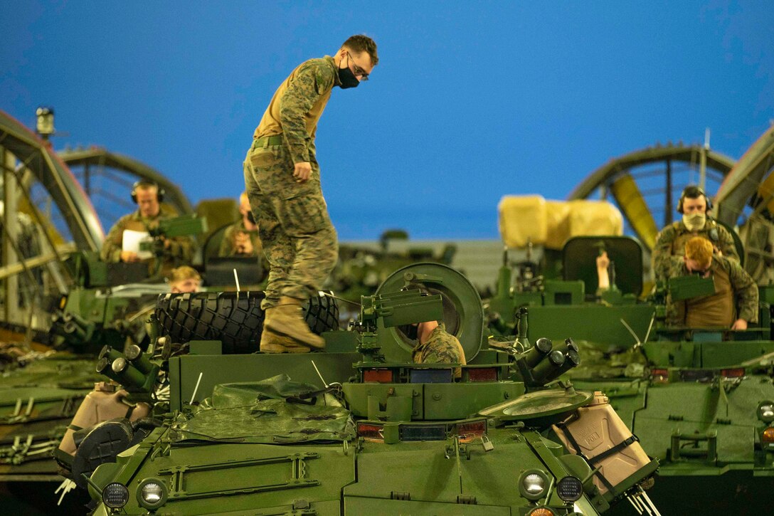 A Marine stands on top of a landing craft vehicle.