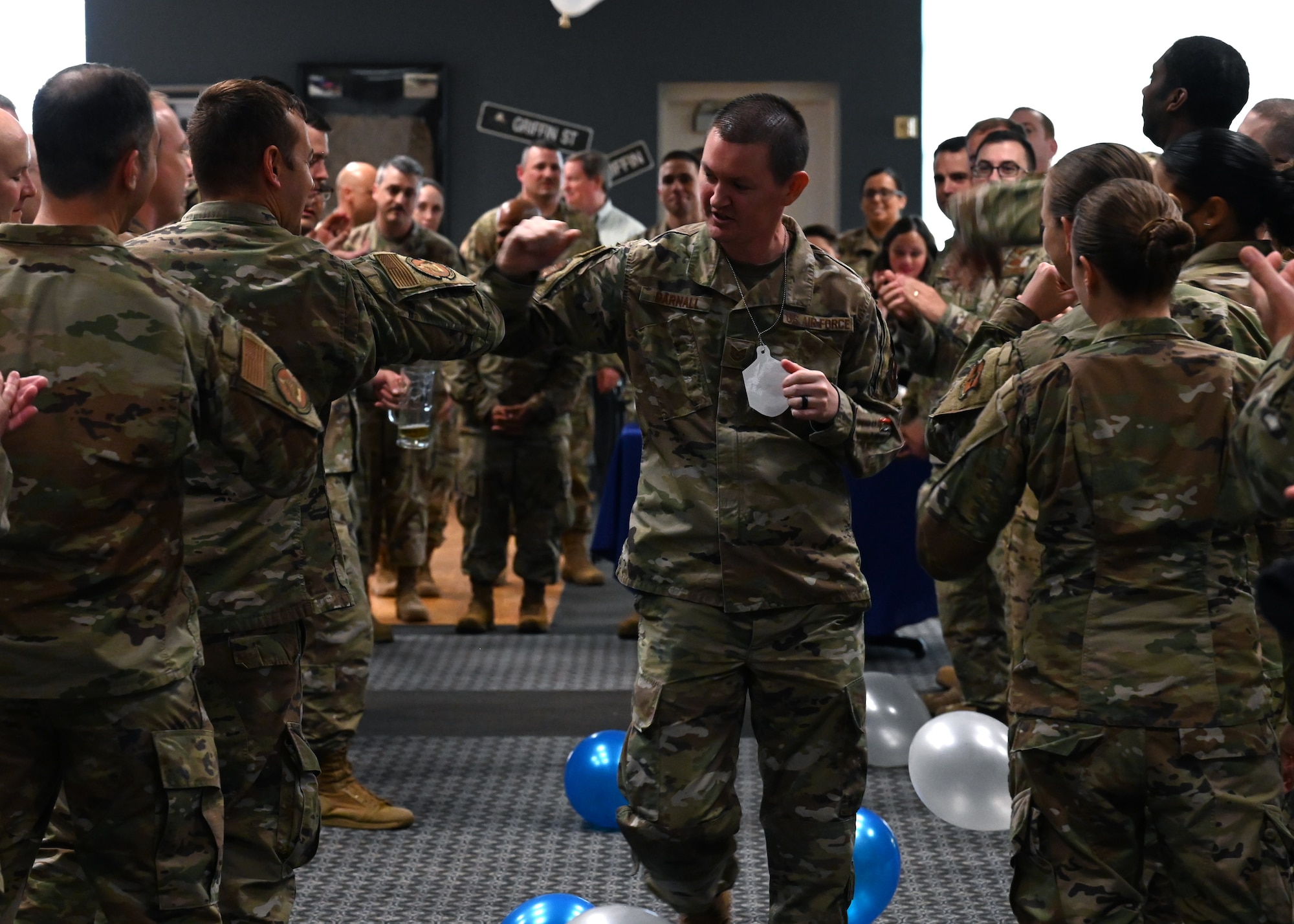 U.S. Air Force Master Sgt. select Bradley Darnall, 313th Training Squadron instructor, runs through a crowd of supporters during the master sergeant release party at the Event Center on Goodfellow Air Force Base, Texas, May 20, 2021. Coworkers and family members congratulated selectees before they received their certificates. (U.S. Air Force photo by Airman 1st Class Michael Bowman)