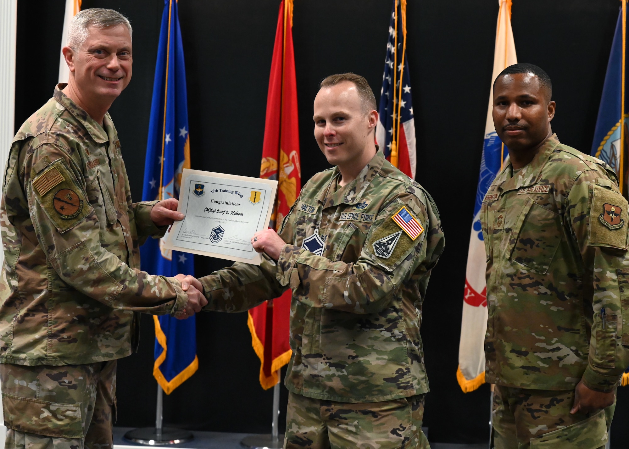 U.S. Air Force Col. Tony England, 17th Mission Support Group commander, presents U.S. Space Force Master Sgt. select Josef Haltom, 315th Training Squadron instructor, his promotion certificate with U.S Air Force Chief Master Sgt. Marcus Washington, 17th Medical Group superintendent during the master sergeant release party at the Event Center on Goodfellow Air Force Base, Texas, May 20, 2021. Master sergeants are transitioning from working as technical experts and frontline supervisors into a dedicated administration role while growing their technical and managerial talents. (U.S. Air Force photo by Airman 1st Class Michael Bowman)