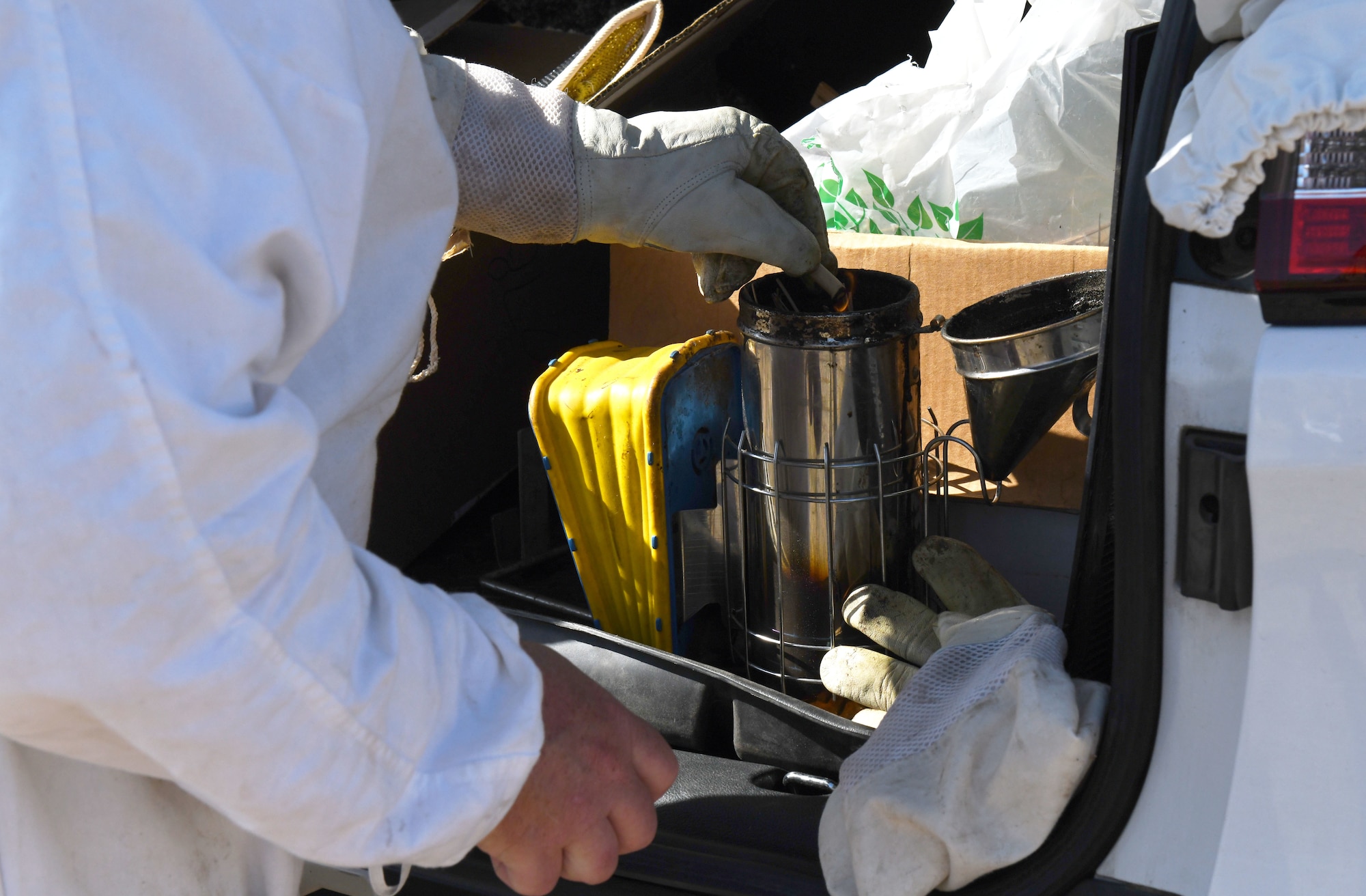 Blaze Baker prepares a bee smoker to smoke out the bees in their hives.