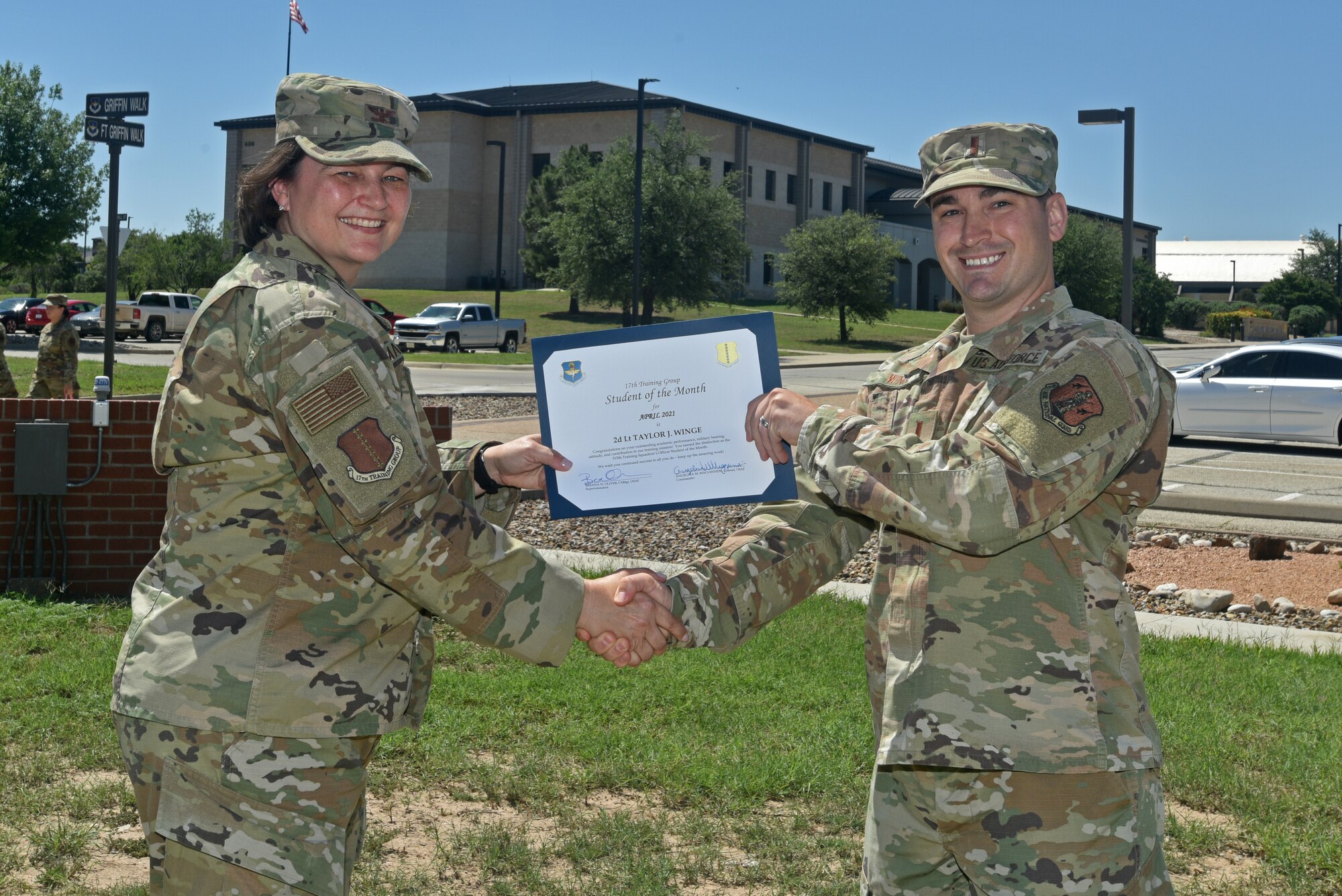 U.S. Air Force Col. Angelina Maguinness, 17th Training Group commander, presents 2nd Lt. Taylor Winge, 315th Training Squadron student, the 17th TRG Student of the Month award for April 2021, outside of the Brandenburg Hall on Goodfellow Air Force Base, Texas, May 21, 2021. The 315th TRS is responsible for training, educating, and mentoring our future intelligence, surveillance, and reconnaissance warriors through innovation. (U.S. Air Force photo by Senior Airman Ashley Thrash)