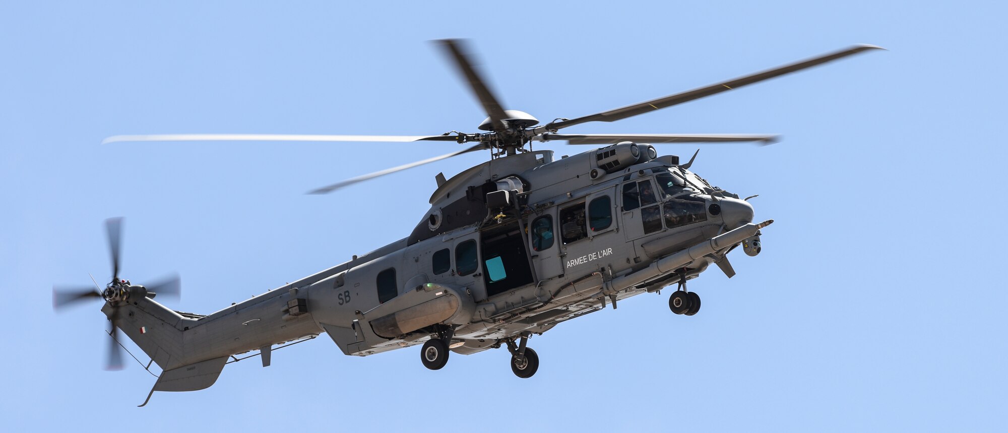 A helicopter flies through the air over a simulated combat zone.