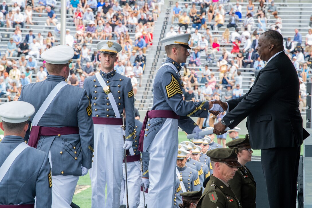 The Secretary of Defense shakes hands with cadets during a graduation ceremony.