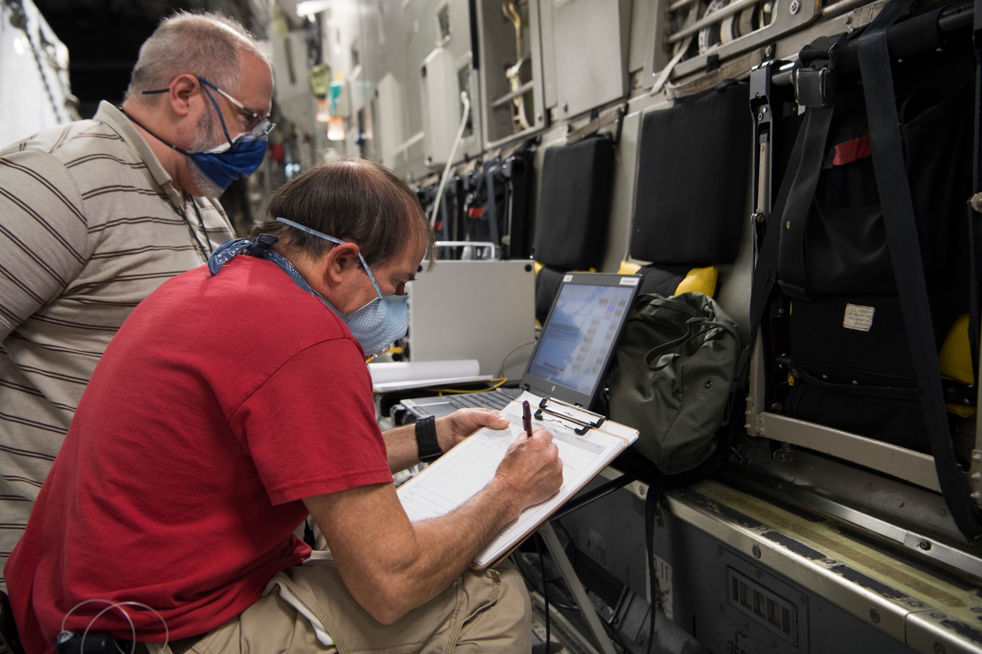 Victor Arca, 28th Test and Evaluation Squadron senior test engineer, and Gabriel Intano, Army Public Health Center microbiologist, record and analyze data after a trial movement and purge through a Portable Bio-Containment Module loaded onto a C-17 Globemaster III at Joint Base Charleston S.C., April 15, 2020. Members from the 28th TES and Army PHC tested the PBCM, which will be exercised regularly to transport COVID patients and medical personnel, all while ensuring the aircrew is impervious to risk of infection. (U.S. Air Force photo by Staff Sgt. Chris Drzazgowski)
