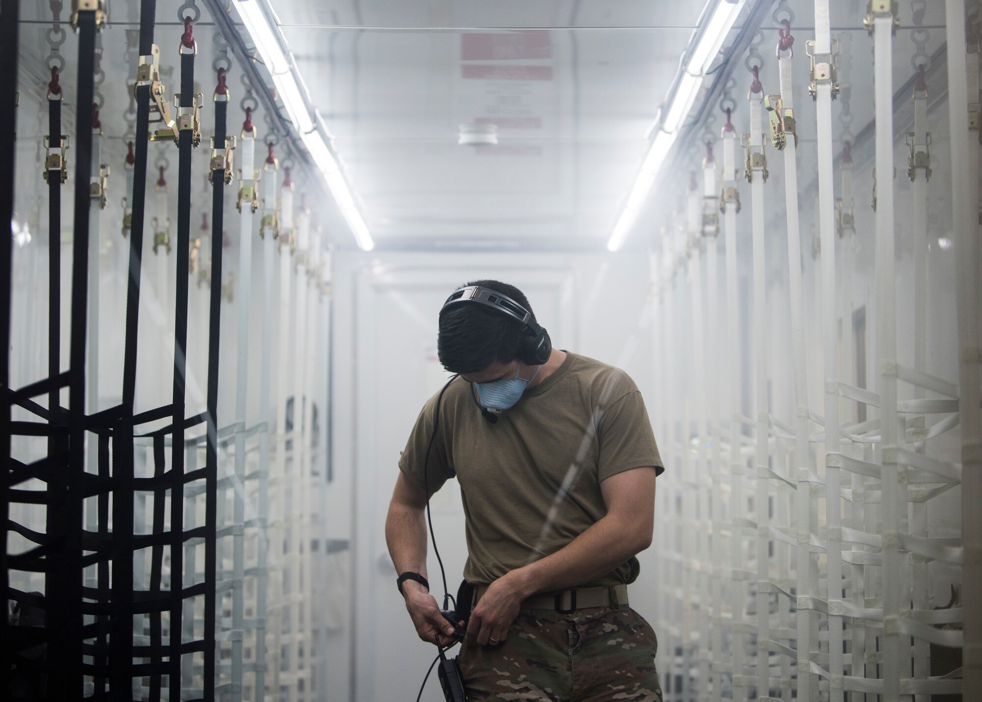 U.S. Air Force Capt. Conor Favo, 28th Test and Evaluation Squadron division chief, adjusts the settings of his headset during the first in-flight testing of a Negatively Pressurized Conex prototype on a C-17 Globemaster III, April 30, 2020. The NPC was rapidly developed and designed to fit inside both C-5 and C-17 aircraft to enable safe transport of up to 28 passengers, as well as teams of medical professionals to medical facilities around the globe. (U.S. Air Force photo by Staff Sgt. Chris Drzazgowski)