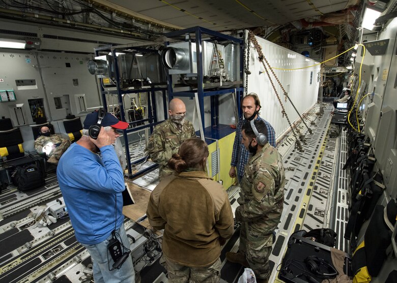 Testers and evaluators from organizations across the Department of Defense discuss the status of in-flight testing conducted to certify a Negatively Pressurized Conex prototype on a C-17 Globemaster III, April 30, 2020. The NPC was rapidly developed and designed to fit inside both C-5 and C-17 aircraft to enable safe transport of up to 28 passengers, as well as teams of medical professionals to medical facilities around the globe. (U.S. Air Force photo by Staff Sgt. Chris Drzazgowski)