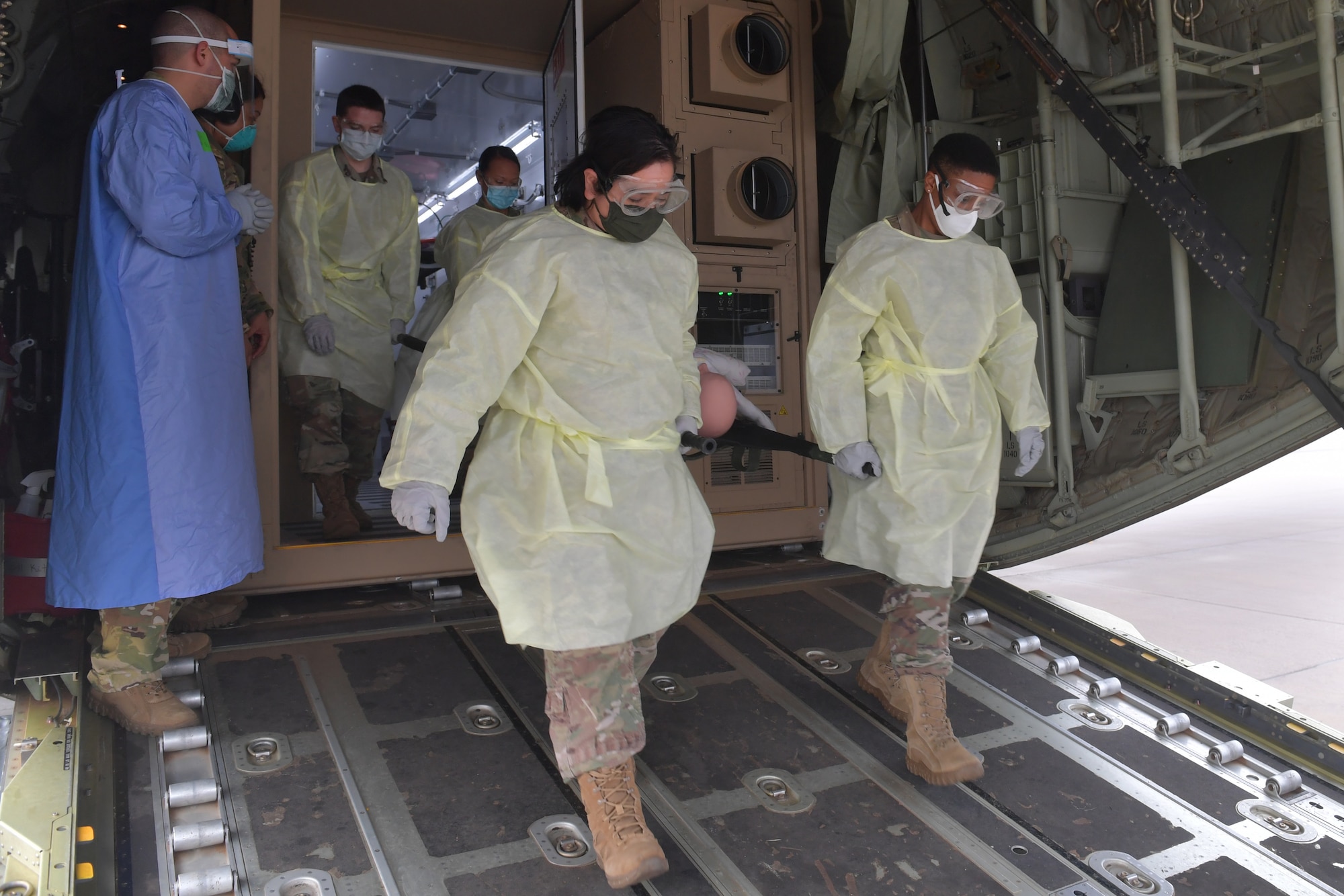 U.S. Air Force Airmen assigned to the 86th Medical Group and 86th Aeromedical Evacuation Squadron carry a simulated COVID-19 patient off of a C-130J Super Hercules aircraft at Ramstein Air Base, Germany, Dec. 18, 2020. The simulated patient was transported within a Negatively Pressurized Conex-Lite aboard the aircraft during an 86th AES training. The NPC-L is a smaller version of the Negatively Pressurized Conex, an isolated containment chamber intended to transport individuals with infectious diseases like COVID-19. (U.S. Air Force photo by Senior Airman John R. Wright)