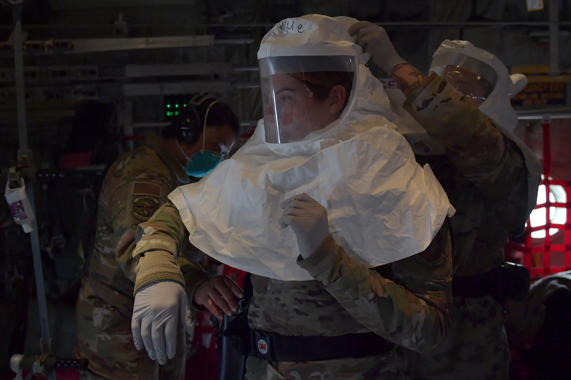 U.S. Air Force Senior Airman Brooke Tjulander, 86th Aerospace Medicine Squadron bioenvironmental engineering technician, right, helps Senior Airman Chelsea Levesque, 86th Medical Support Squadron biomedical equipment technician, secure a powered air-purifying respirator hood during a COVID-19 patient movement training at Ramstein Air Base, Germany, Dec. 18, 2020. After a simulated patient was transported on a Negatively Pressurized Conex-Lite, a bioenvironmental engineering and biomedical equipment team performed decontamination procedures. The training presented Airmen with various patient transfer scenarios and ended with a proof-of-concept flight on a C-130J Super Hercules aircraft. (U.S. Air Force photo by Senior Airman John R. Wright)