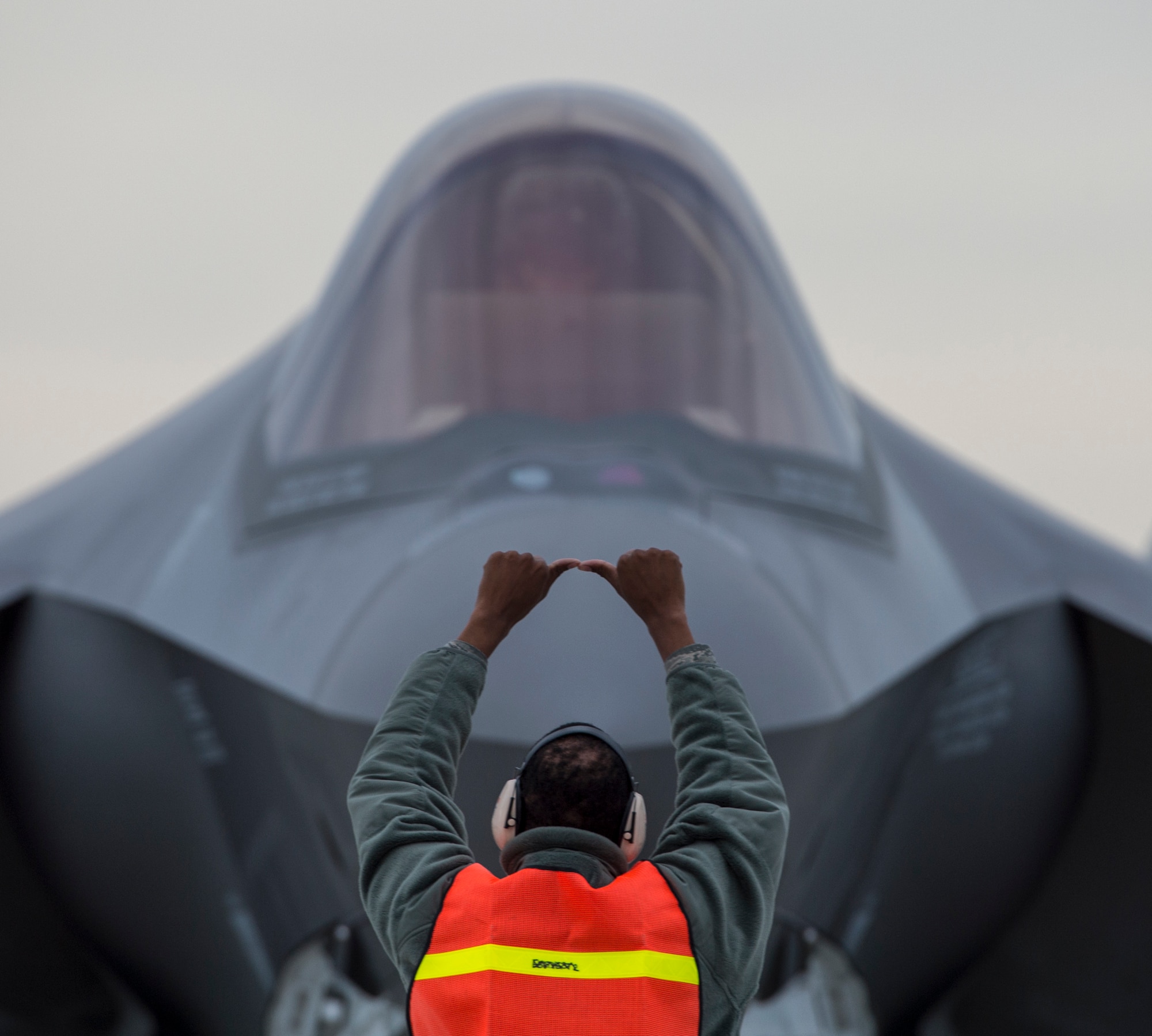 Staff Sgt. Quincy Robinson, a weapons load crew member from the 31st Test and Evaluation Squadron, signals to chock the tires of an F-35 Lightning fighter jet from the 53rd TES before arming and takeoff from Mountain Home Air Force Base, Idaho, Feb. 17, 2016. (U.S. Air Force photo/Tech Sgt. Brian Ferguson)
