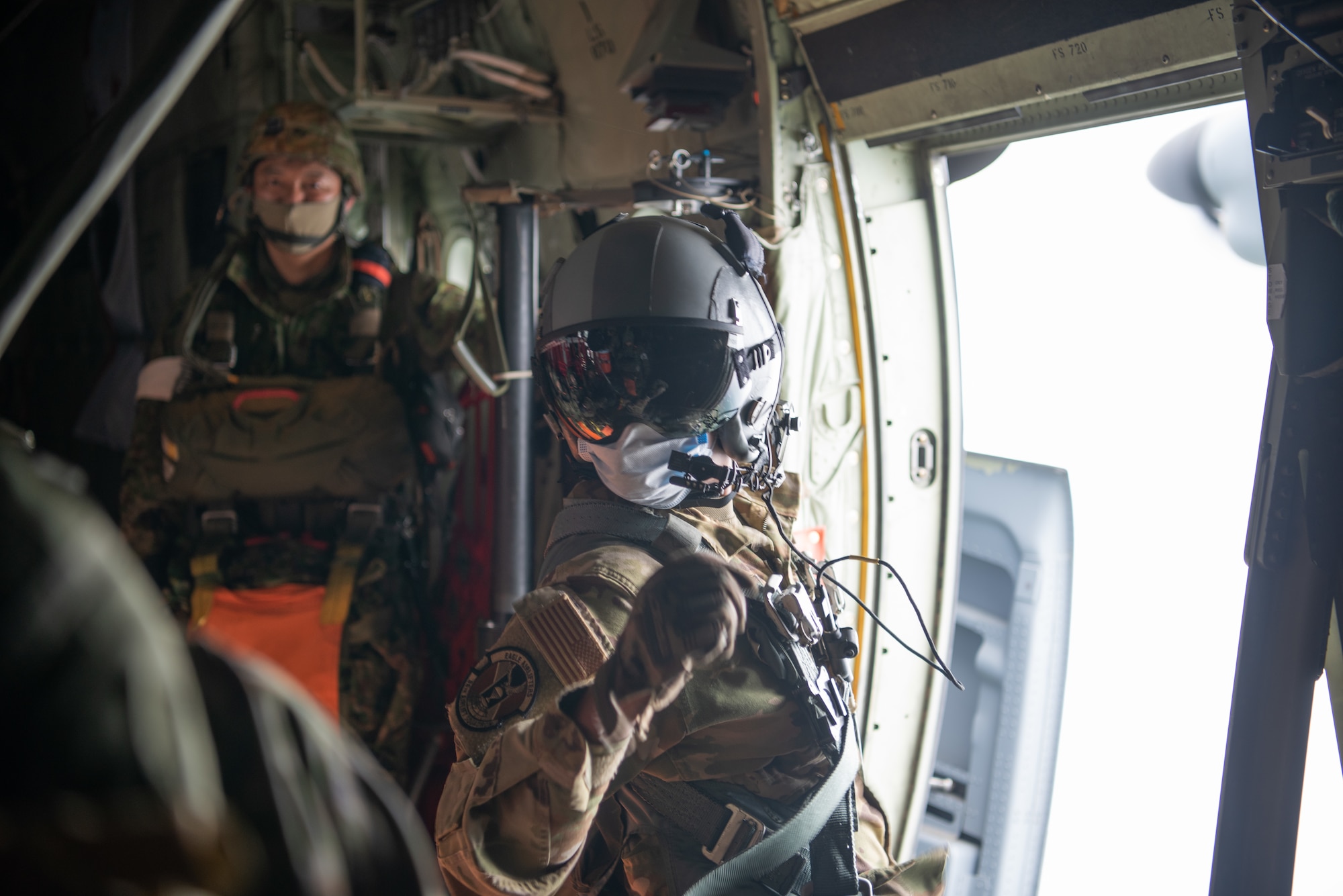Airman with flight mask and equipment at the personnel door of the C-130J Super Hercules aircraft.