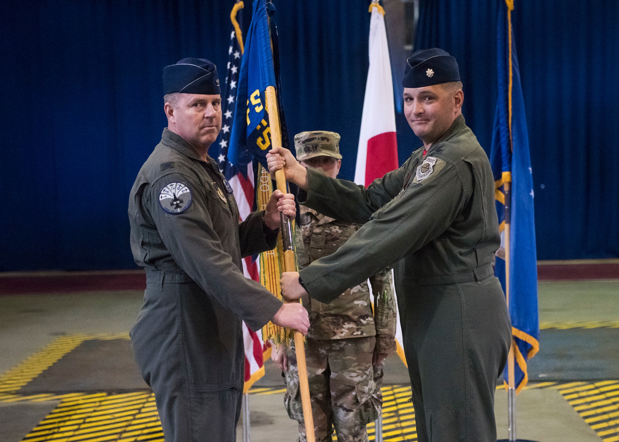 Individuals participate in a change of command ceremony indoors