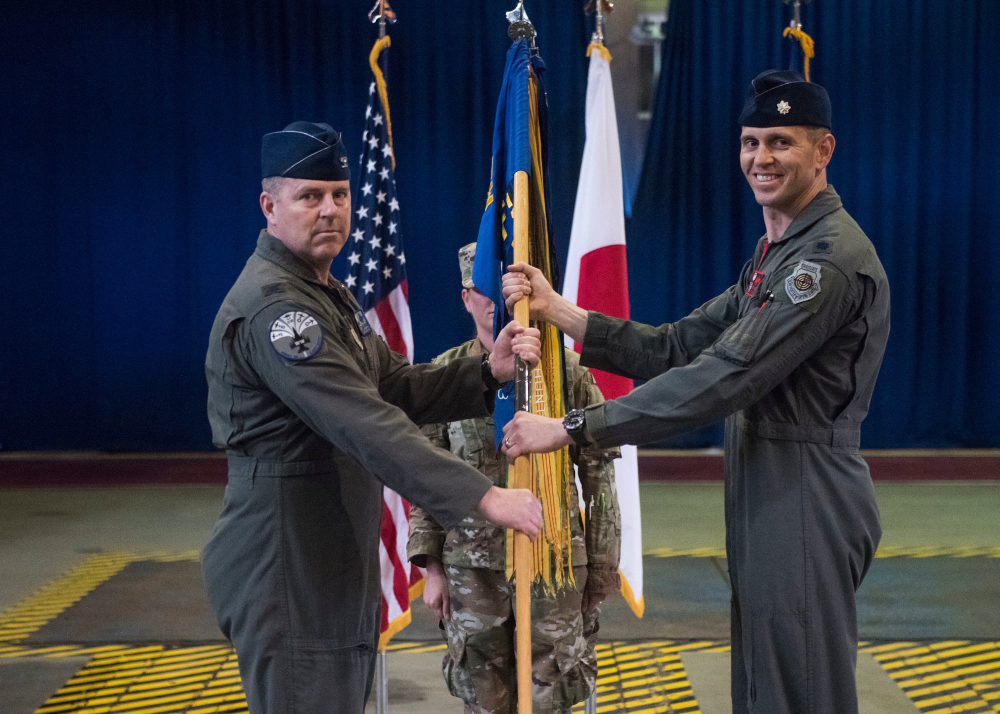 Individuals participate in a change of command ceremony indoors