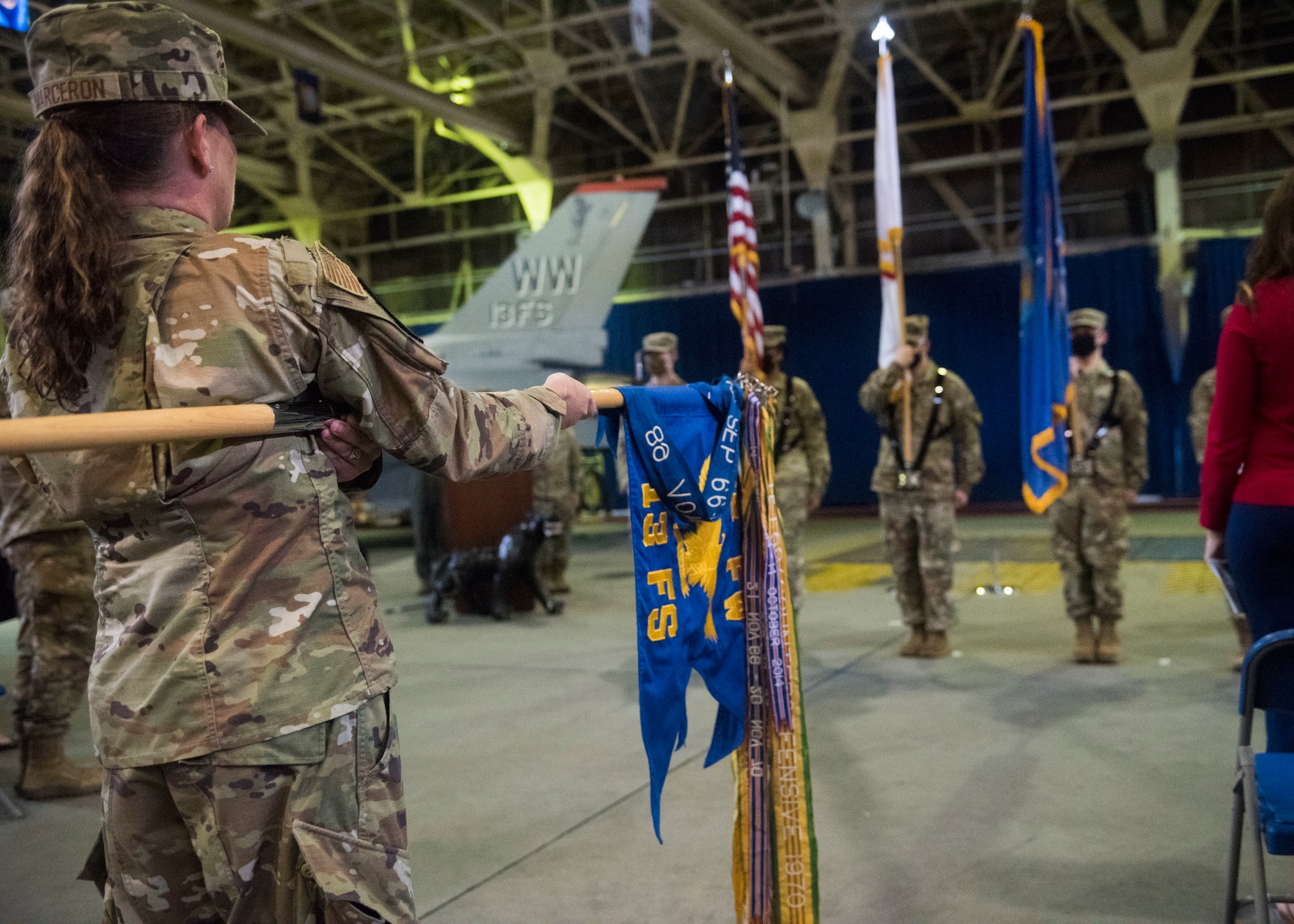 Individuals participate in a change of command ceremony indoors